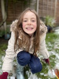 Portrait of smiling girl paying outside home during winter