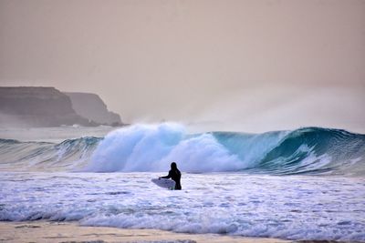 Man surfing in sea against sky