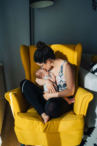 Rear view of woman sitting on sofa at home