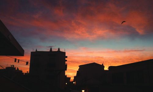 Silhouette of building against cloudy sky at sunset