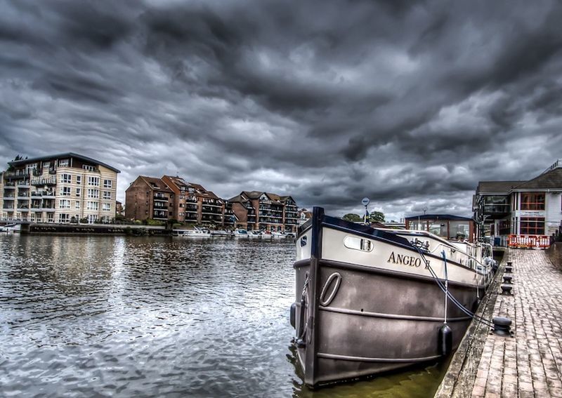 BOAT IN RIVER AGAINST CLOUDY SKY