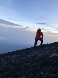 Man standing on rock against sky during sunset