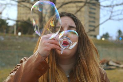 Close-up of woman blowing bubble wand