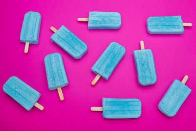 Blue popsicles on a pink background