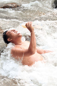 Midsection of shirtless boy splashing water