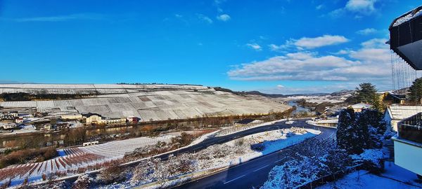 Road by buildings against blue sky during winter
