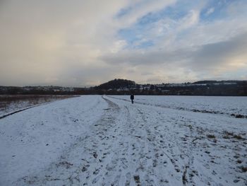 Snow covered landscape against sky during sunset