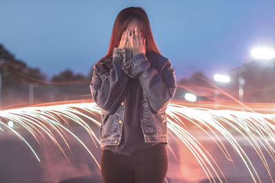 Young woman standing by light painting