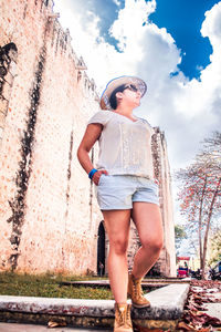 Young woman standing on retaining wall against sky