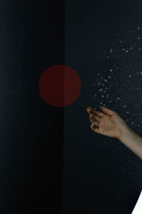 Cropped hand of woman against black background