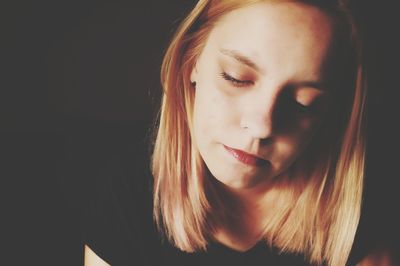 Close-up of thoughtful woman against black background