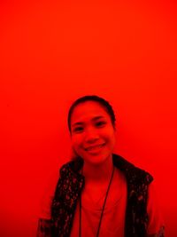 Portrait of smiling woman against red background