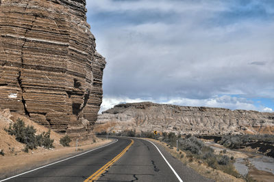 Road by rock formation against sky