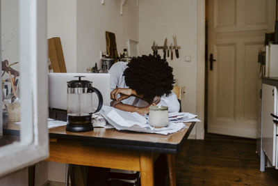 Young businesswoman with head down on table in living room