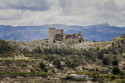 Castle on mountain against cloudy sky