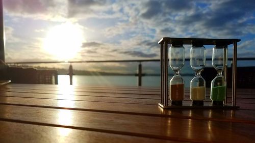 Close-up of glass table by sea against sunset sky