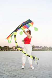 Full length of woman holding multi colored umbrella against sky