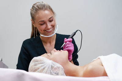 Smiling beautician treating customer at spa