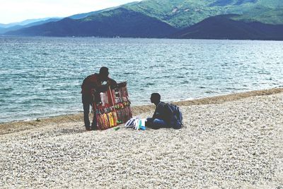 People sitting on beach against sky