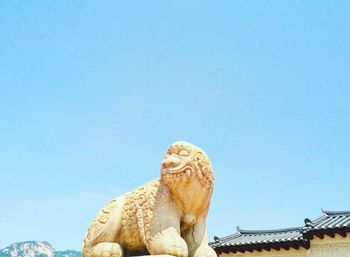 Low angle view of old statue against clear blue sky