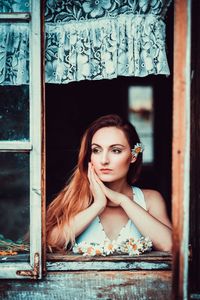 Portrait of young woman against window