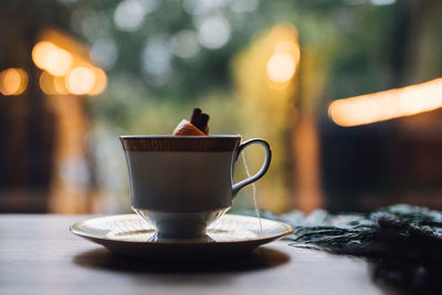 Teacup hot toddy cinnamon orange with bokeh lights in background