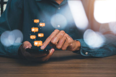 Close-up of man using smart phone on table