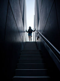 Low angle view of woman standing on steps amidst walls