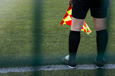 Low section of man with flag standing on soccer field