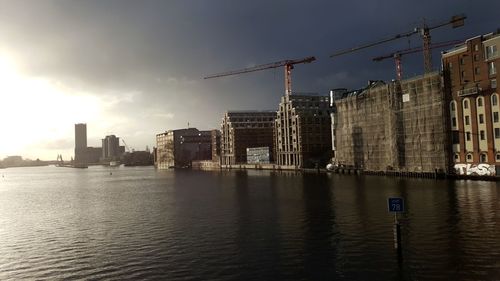 Buildings by river against sky in city