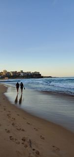 People at beach against clear sky