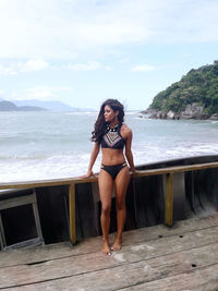 Full length portrait of young woman standing at beach