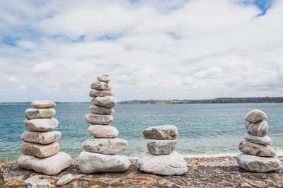 Stack of stones in sea against sky