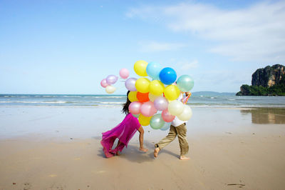 Couple walking on beach with balloons