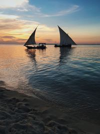 Sailboats on sea against sky during sunset