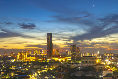 Illuminated buildings in city against sky