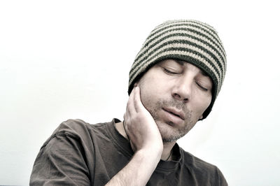 Close-up of young man suffering from toothache against white background