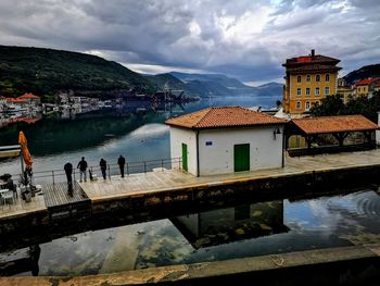 Buildings by lake against sky in city