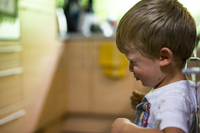 Side view of little boy making face at home