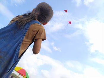 Low angle view of woman flying kite against sky