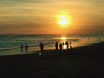 Silhouette people on beach against sky during sunset