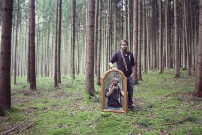 Portrait of mature man on tree trunk in forest