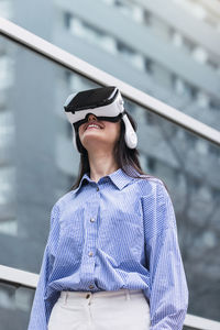 Smiling woman wearing virtual reality simulator on sunny day