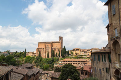 Buildings in city against cloudy sky