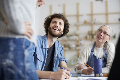 Male and female students listening to instructor while learning drawing in art class