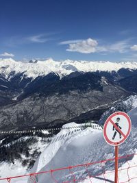 Road sign on snow covered mountain against sky