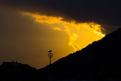 Silhouette street against sky during sunset