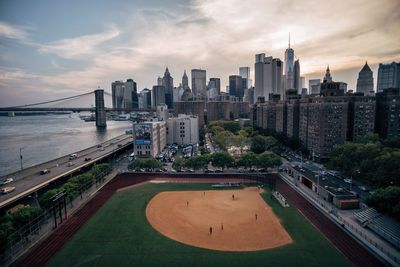 High angle view of baseball diamond by river in city against sky