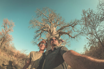 Low angle view of young couple standing on tree