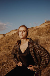 Portrait of woman standing on field against sky